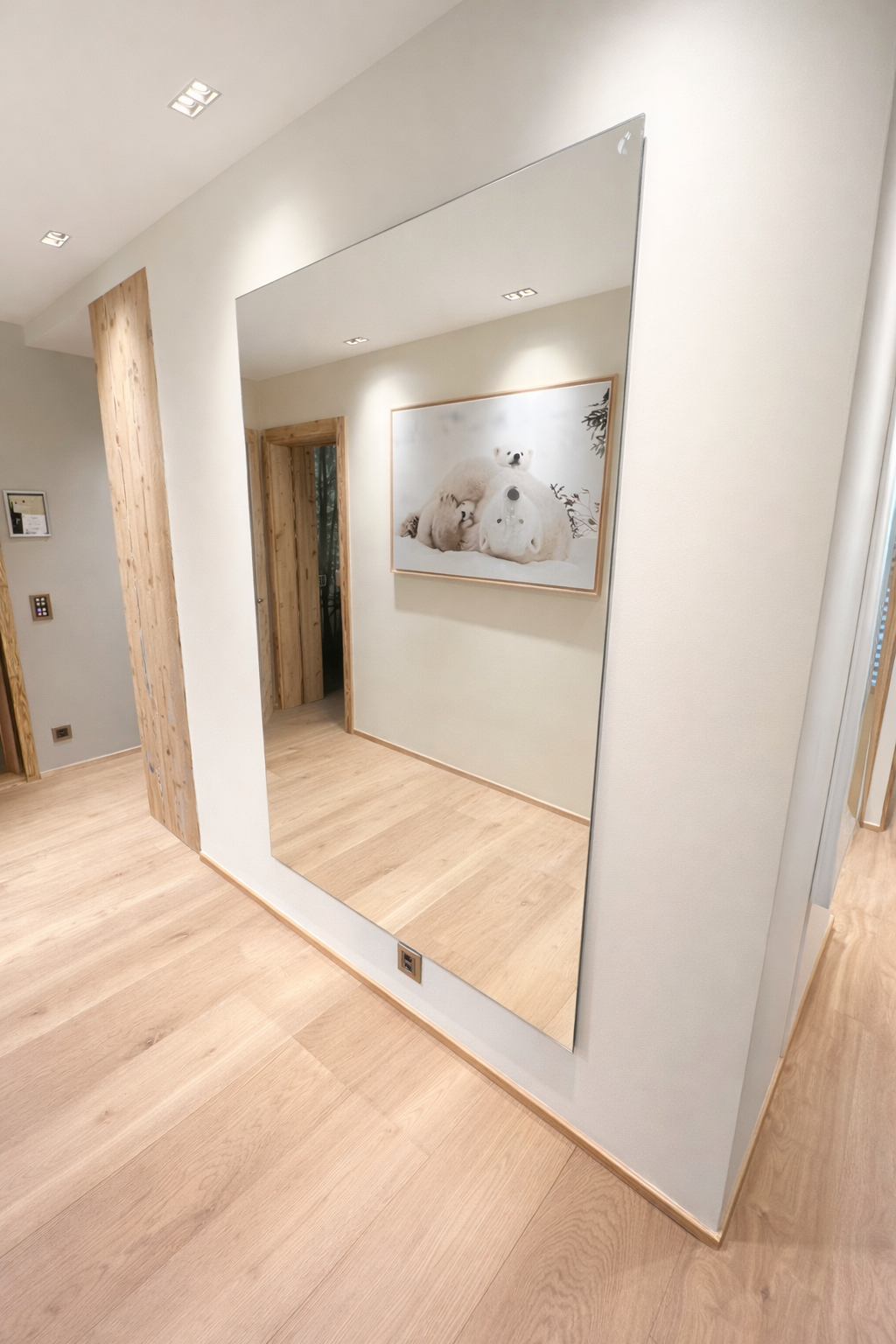Grand miroir mural sur mesure installé dans un couloir contemporain avec parquet en bois clair.