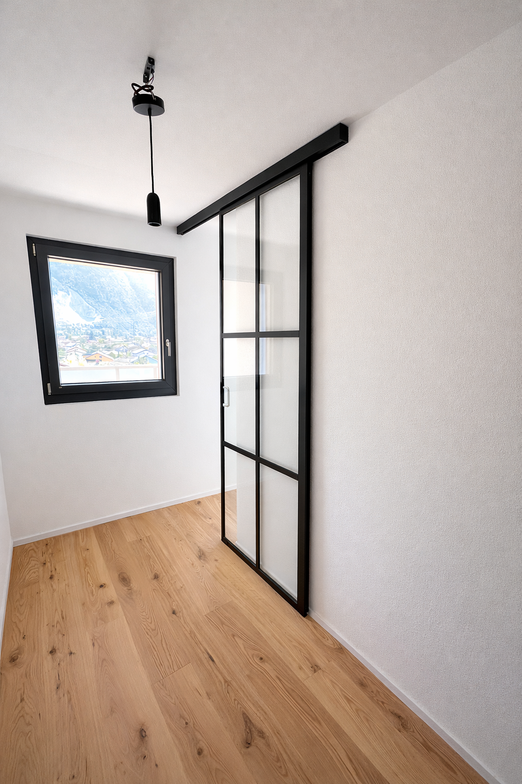 Porte coulissante en verre style verrière avec structure noire en acier.